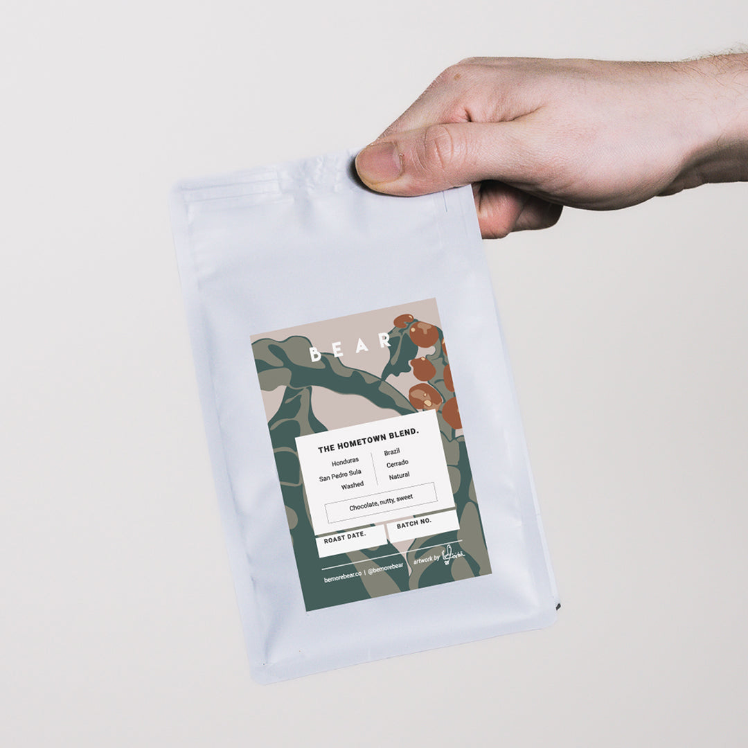 A hand holding a bag of BEAR's Hometown Blend coffee